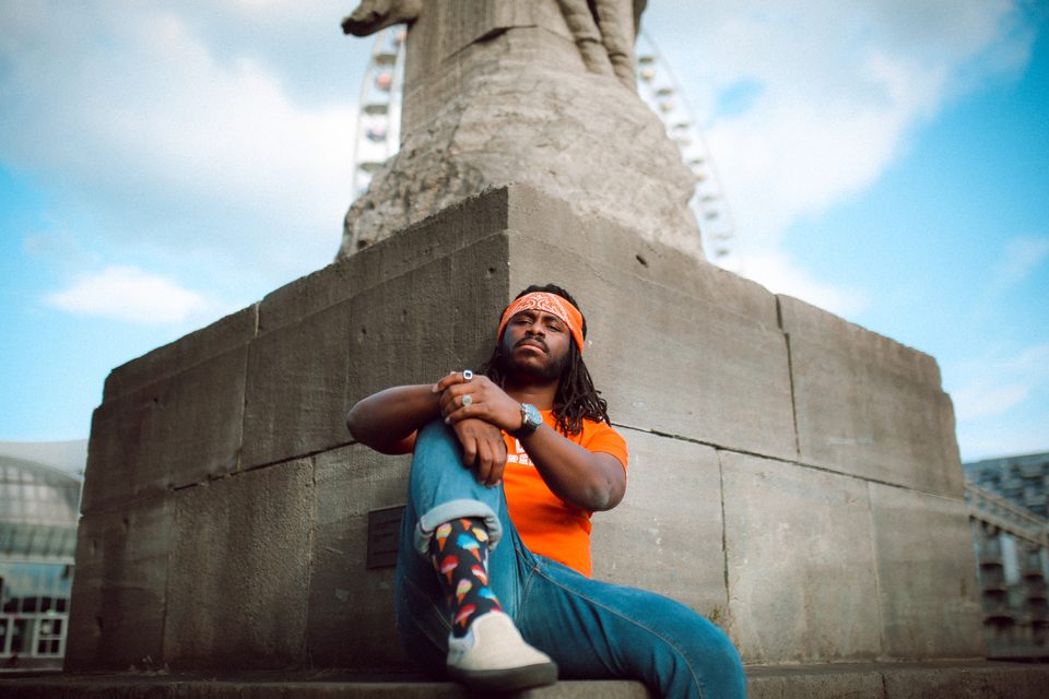 DJ Freegah assis en extérieur près d'un monument urbain
